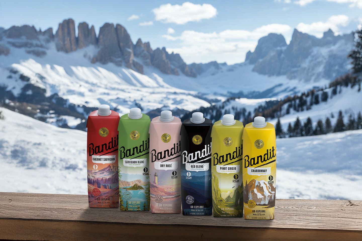 A landscape scene in winter with Bandit products lined up in the foreground on a wood railing with rocky mountains and alpine trees and snow in the background